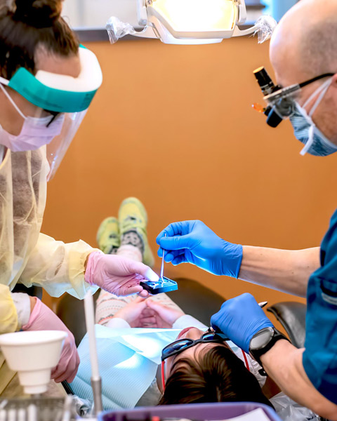 Dental Hygiene program student working on patient's teeth with instructor