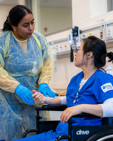 Two nursing program students training in nursing lab